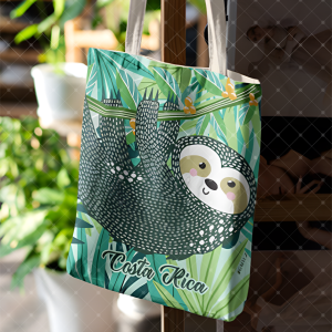 Tote bag celeste con oso perezoso entre hojas tropicales y correas claras de algodón.